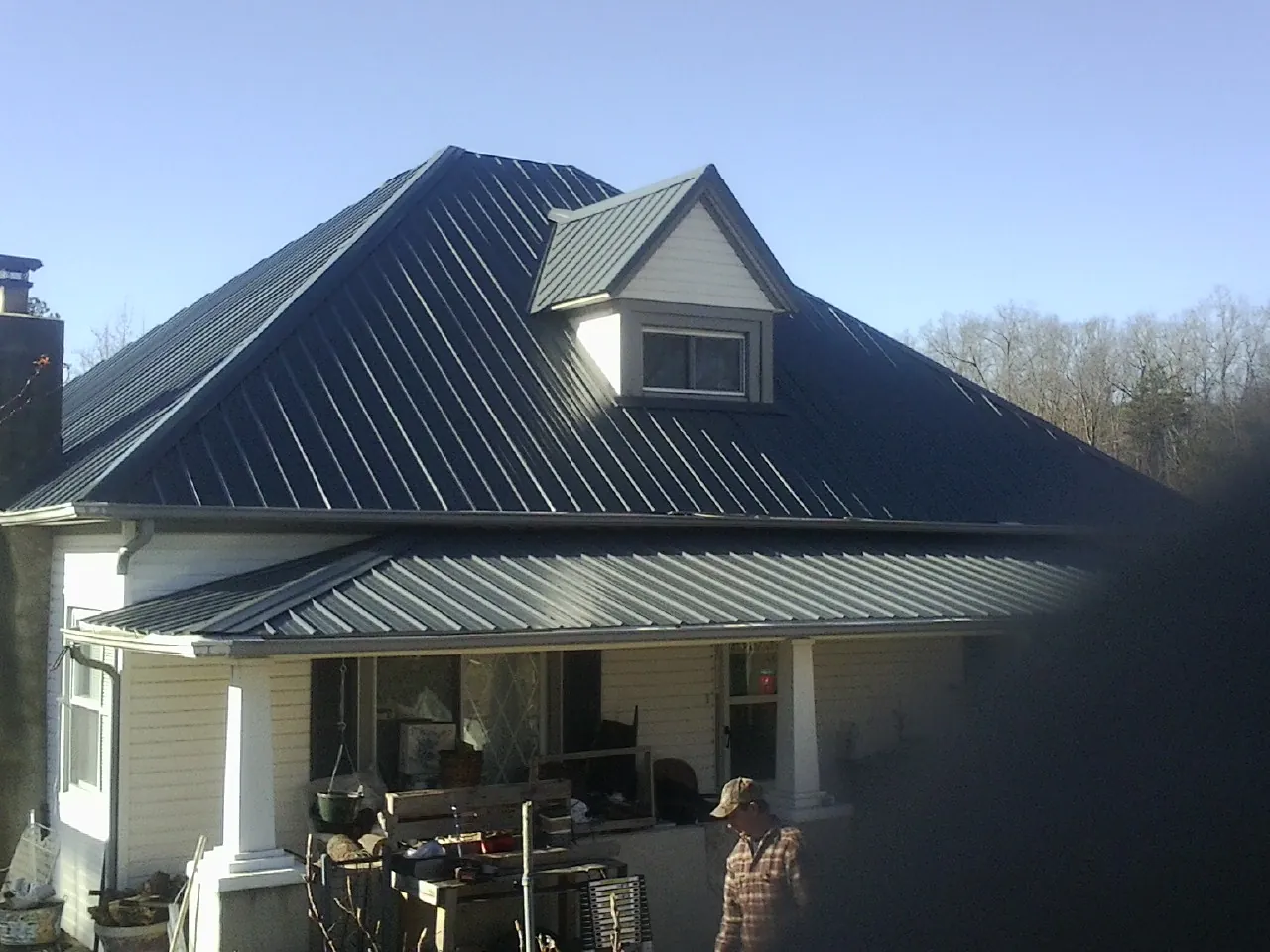 Dark blue standing seam metal roof with a dormer above a front porch in Afton